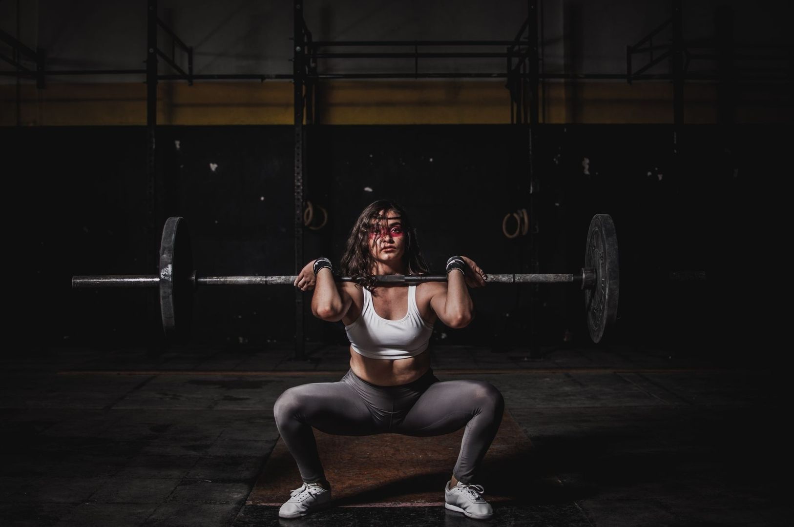Kvinna gör en djup knäböj med skivstång i ett gym